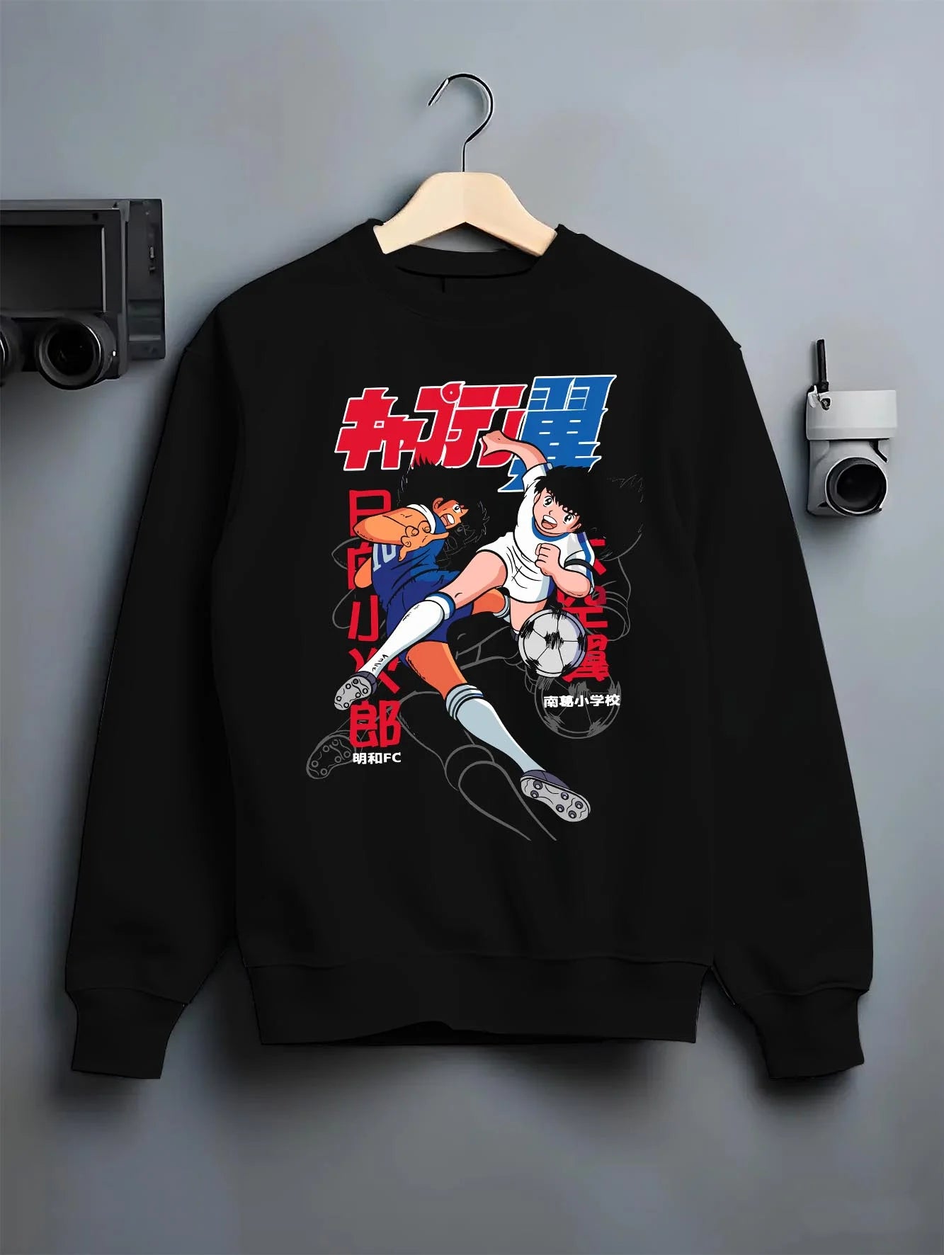 Black crewneck sweatshirt on hanger with Tsubasa Duo Hoodie Captain Tsubasa Soccer Team Play graphic bold anime graphic.