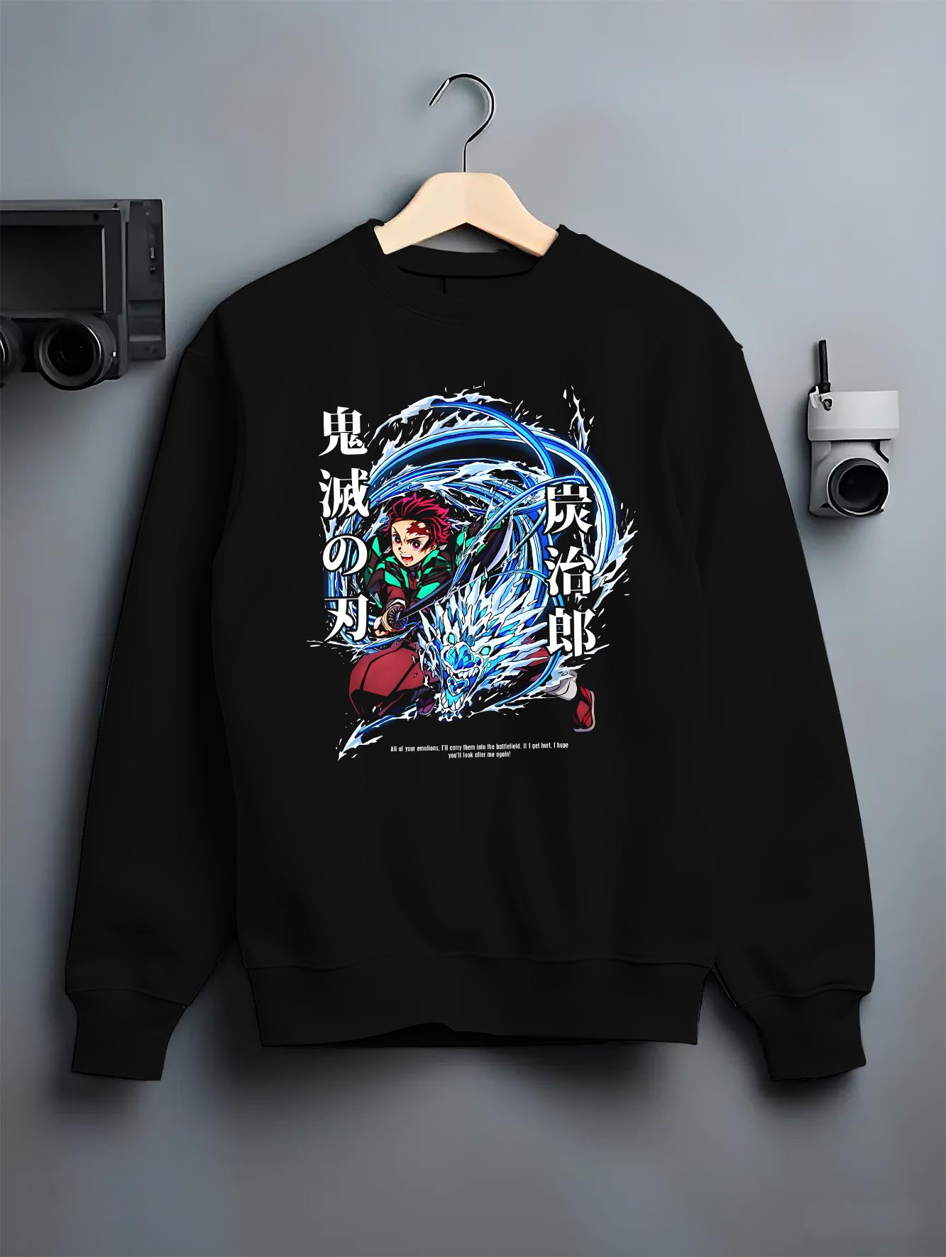 Black crewneck sweatshirt on a hanger against a grey wall, featuring Tanjiro Kamado Demon Slayer animation streetwear graphic with Water Breathing dragon and sword motion.