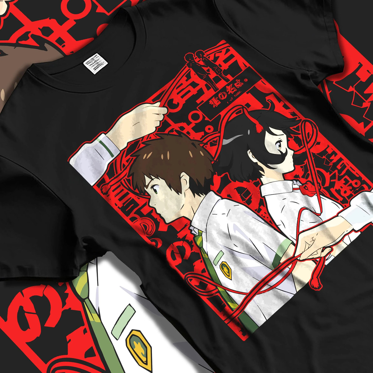 Black T-shirt laid flat with natural folds featuring Taki and Mitsuha red thread Your Name artwork.