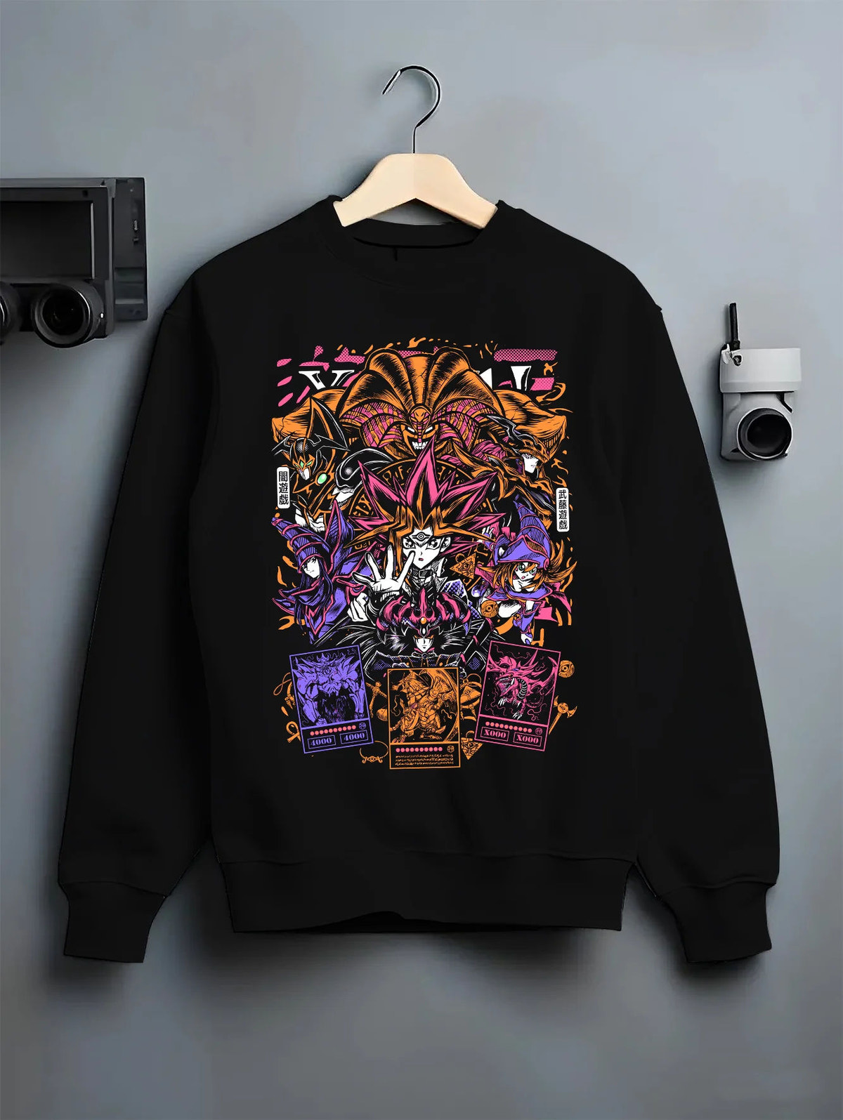 Black crewneck sweatshirt on hanger with Yu-Gi-Oh! monsters and duelling cards collage illustrated back graphic