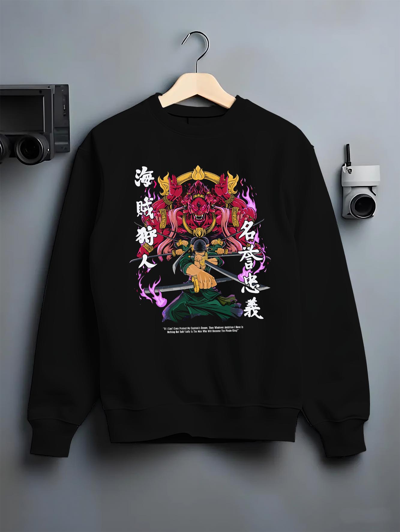 Black crewneck sweatshirt on a hanger against a grey wall, featuring Zoro One Piece shonen battle design with fiery manga panel inspired Japanese streetwear style.