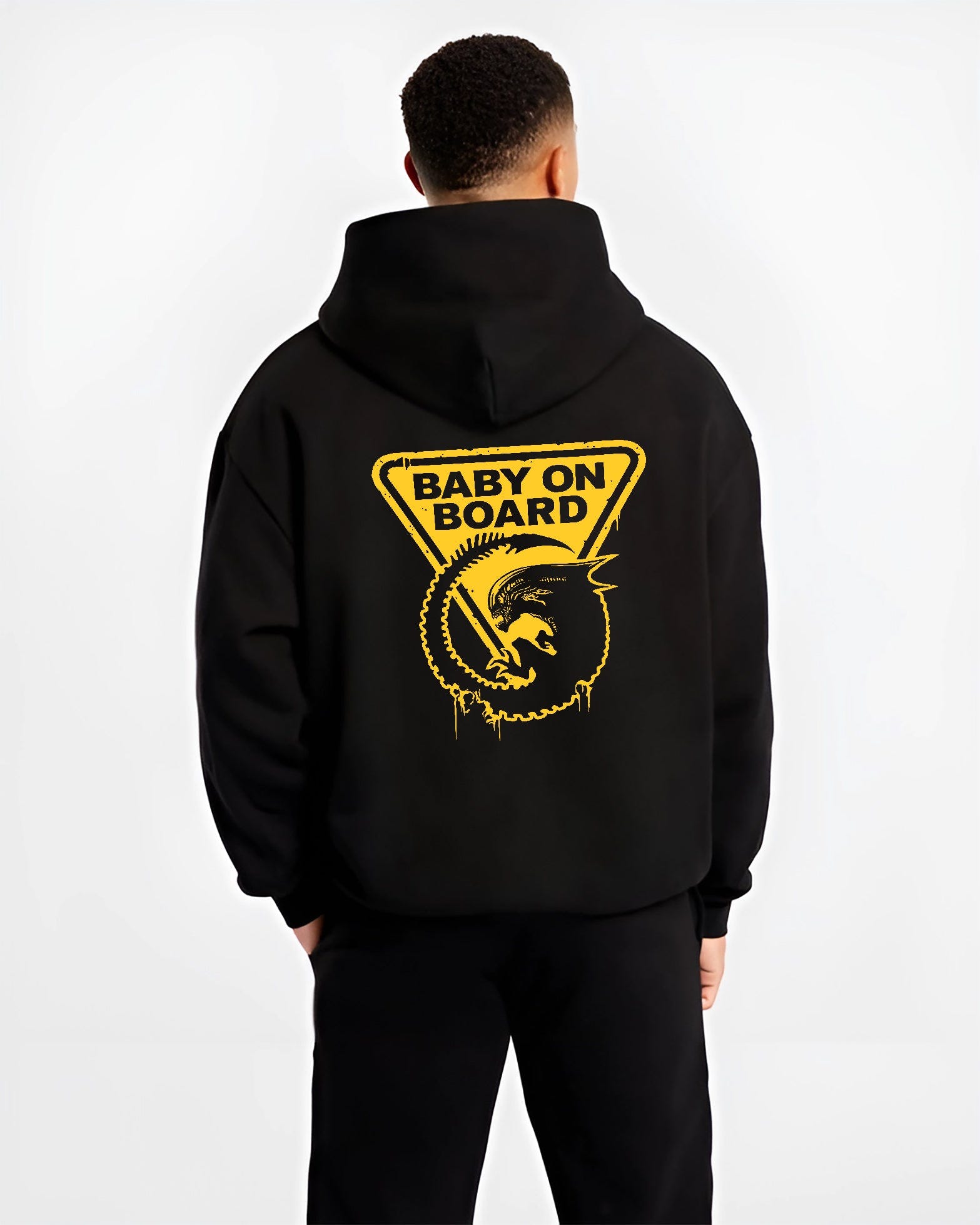 Black hoodie on male model, back view, Alien baby on board warning sign artwork in retro sci-fi film style with paint drips.