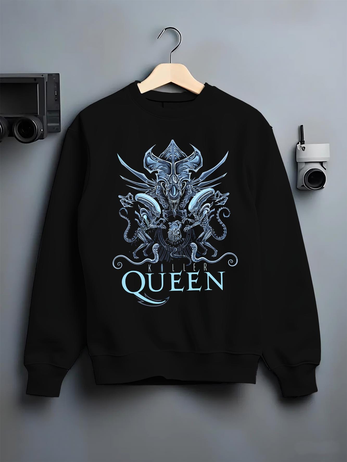 Black crewneck sweatshirt on hanger against grey wall, Alien Xenomorph Queen “Killer Queen” retro sci-fi back graphic with cool blue highlights.