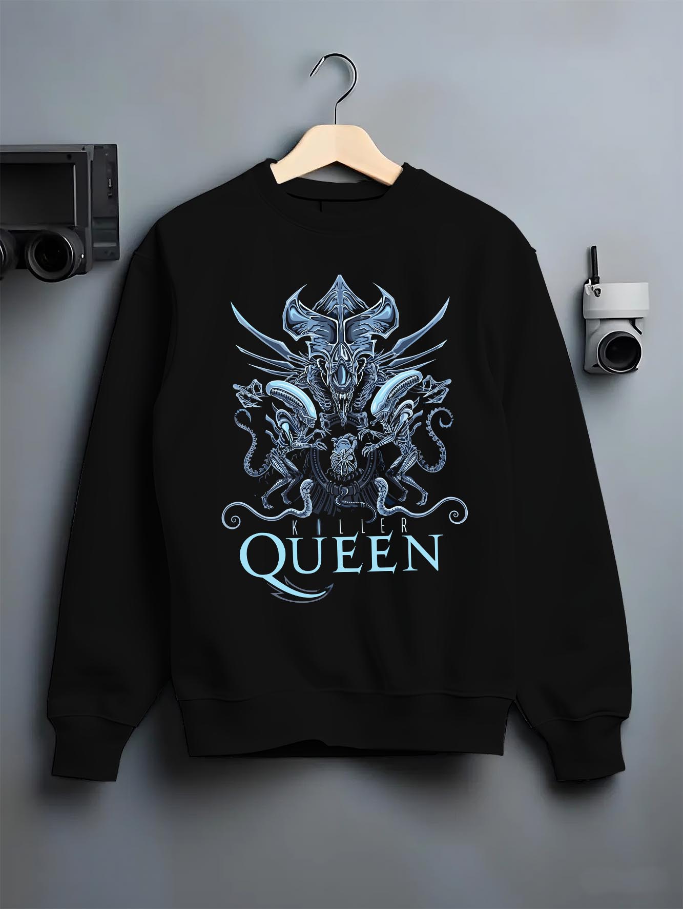 Black crewneck sweatshirt on hanger against grey wall, Alien Xenomorph Queen “Killer Queen” retro sci-fi back graphic with cool blue highlights.