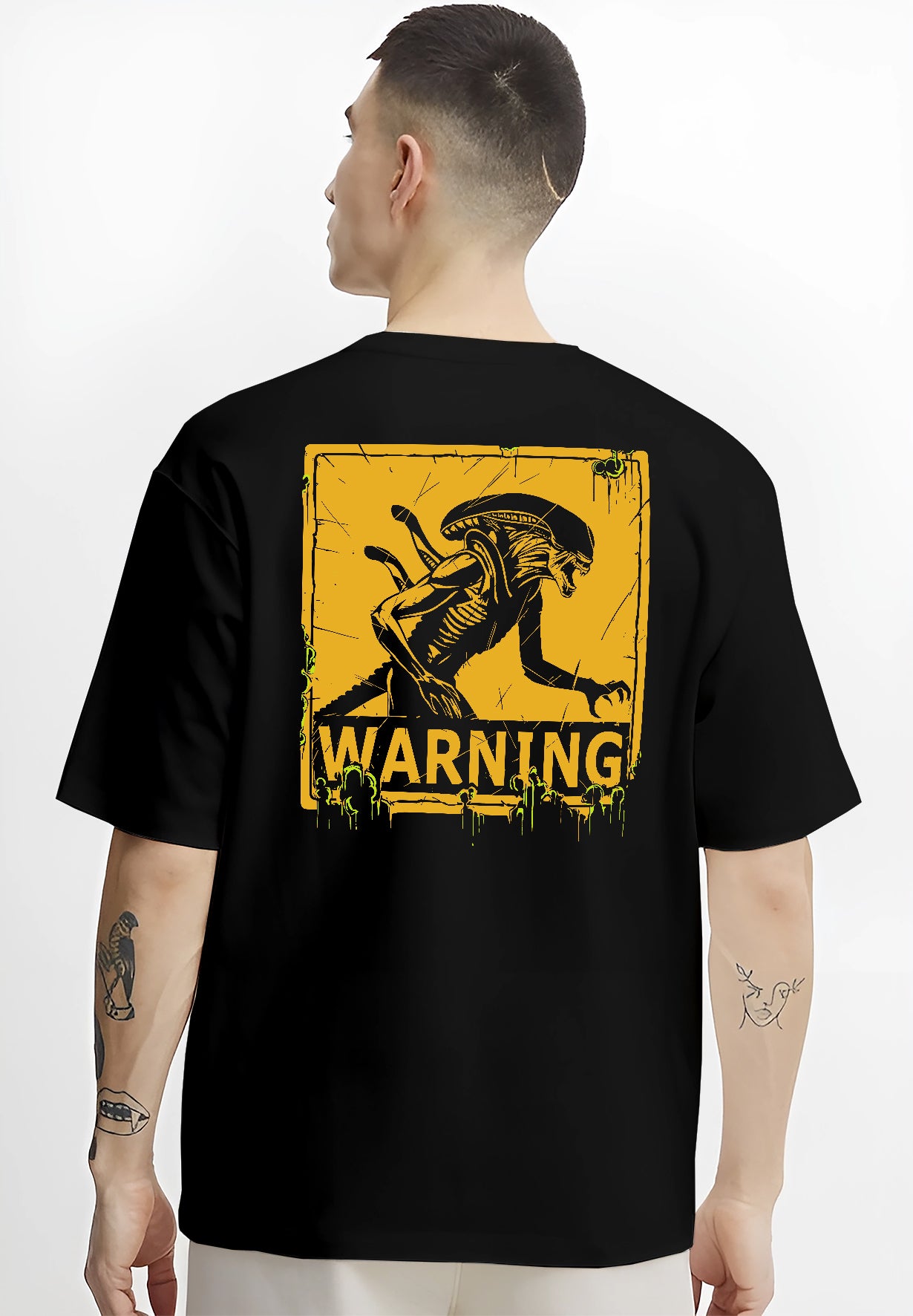 Black T-shirt on male model, back view, Alien Xenomorph warning sign artwork, retro sci-fi film style with green drips.