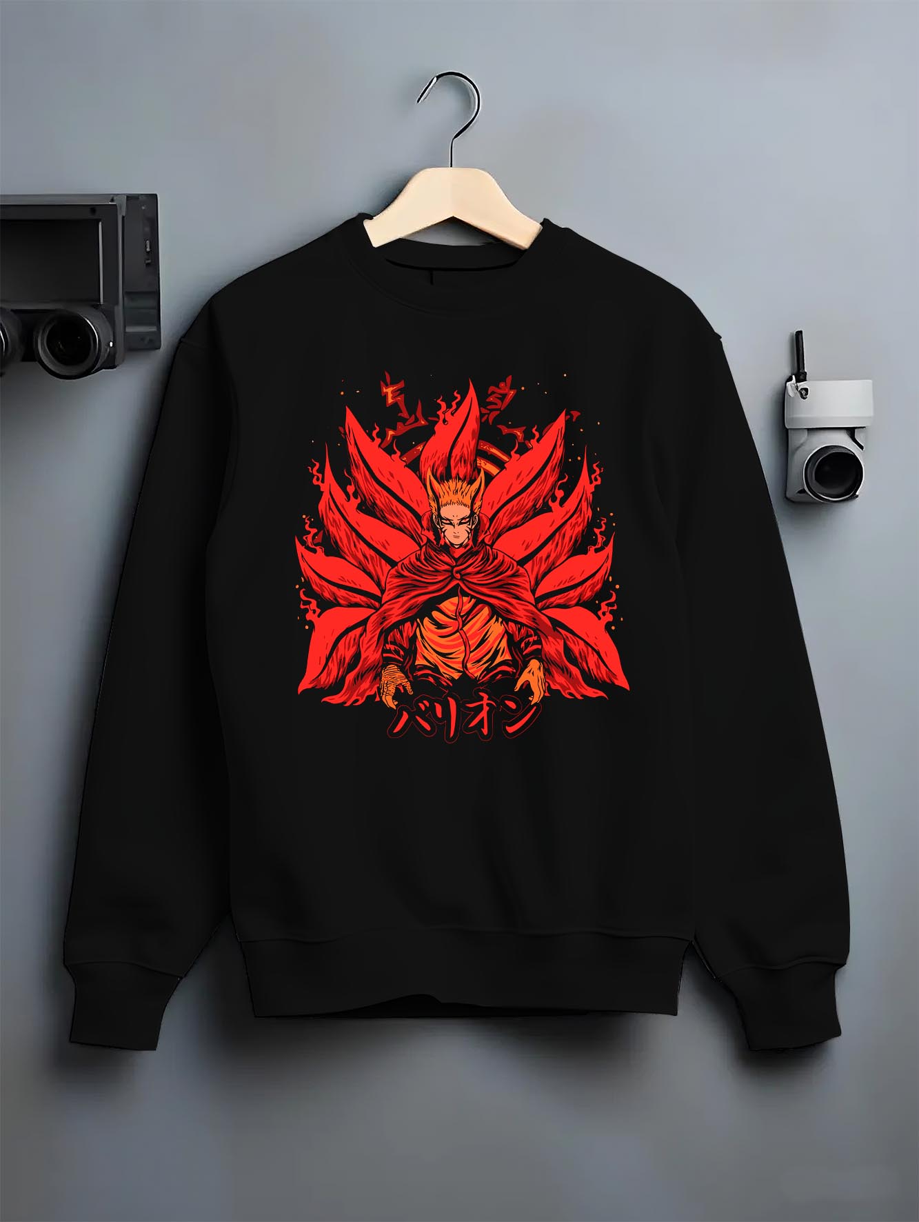 Black crewneck sweatshirt on a hanger against a grey wall, featuring Naruto Baryon Mode shonen battle retro manga artwork with fiery anime poster inspired design.