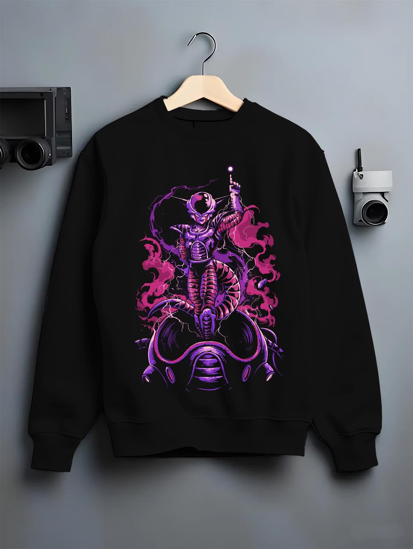 Black crewneck sweatshirt on a hanger against a grey wall, featuring Frieza Dragon Ball anime graphic with retro manga panel style and purple vaporwave aesthetic.