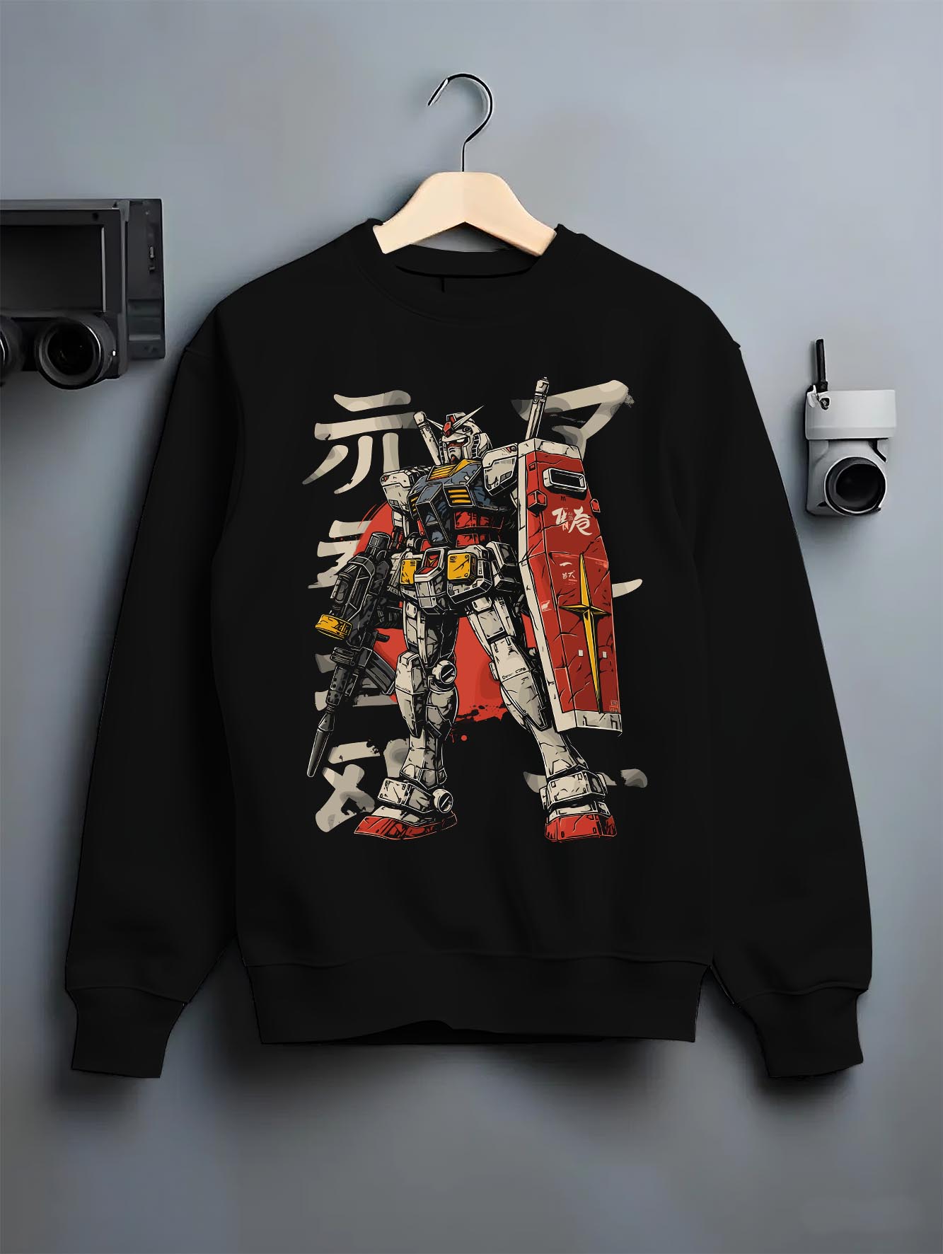 Black crewneck sweatshirt on a hanger against a grey wall, featuring Gundam retro streetwear graphic with detailed mecha suit and bold anime poster inspired design.