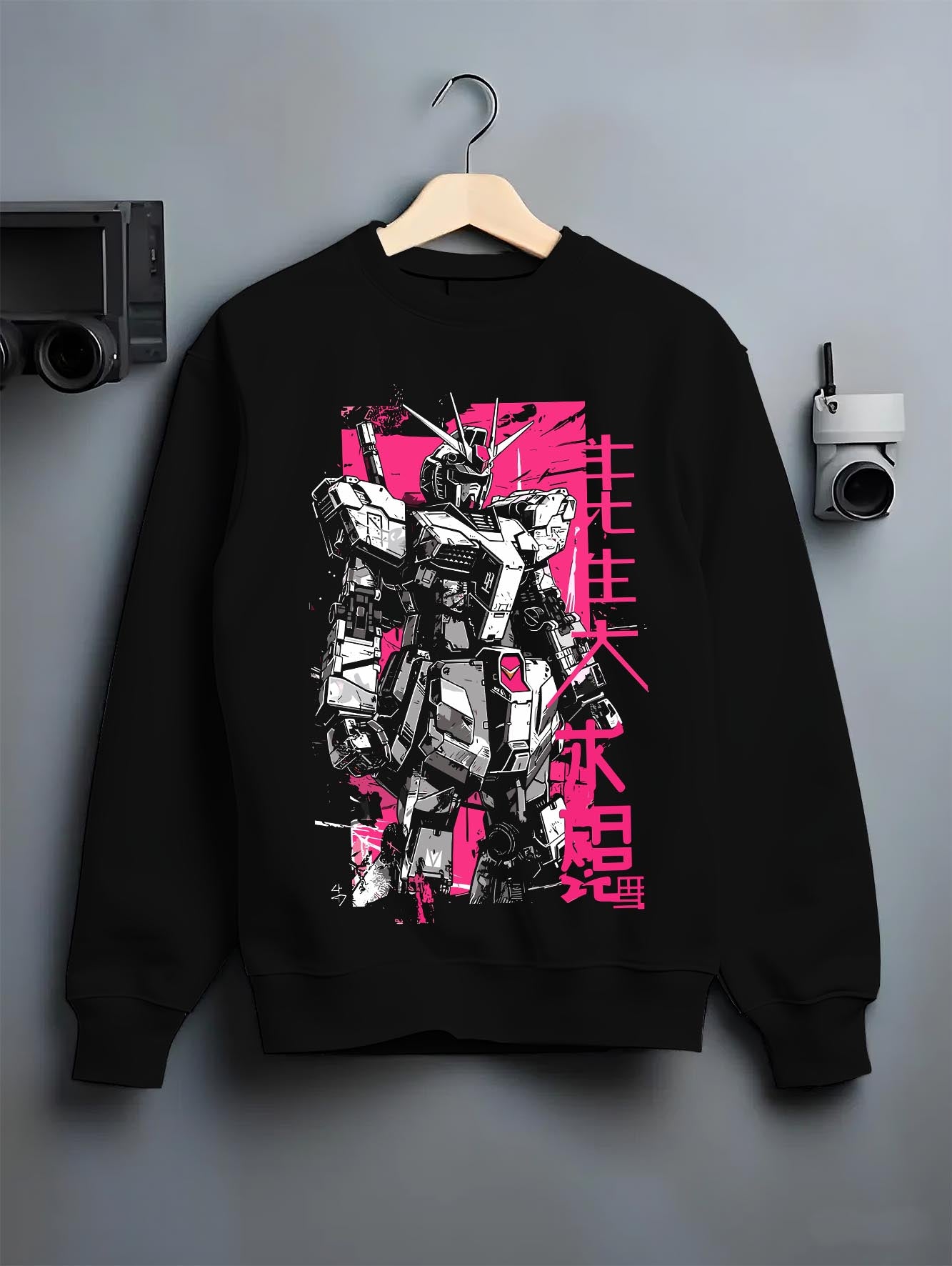 Black crewneck sweatshirt on hanger against grey wall, showing Gundam retro mecha back graphic with pink poster style and Japanese lettering.