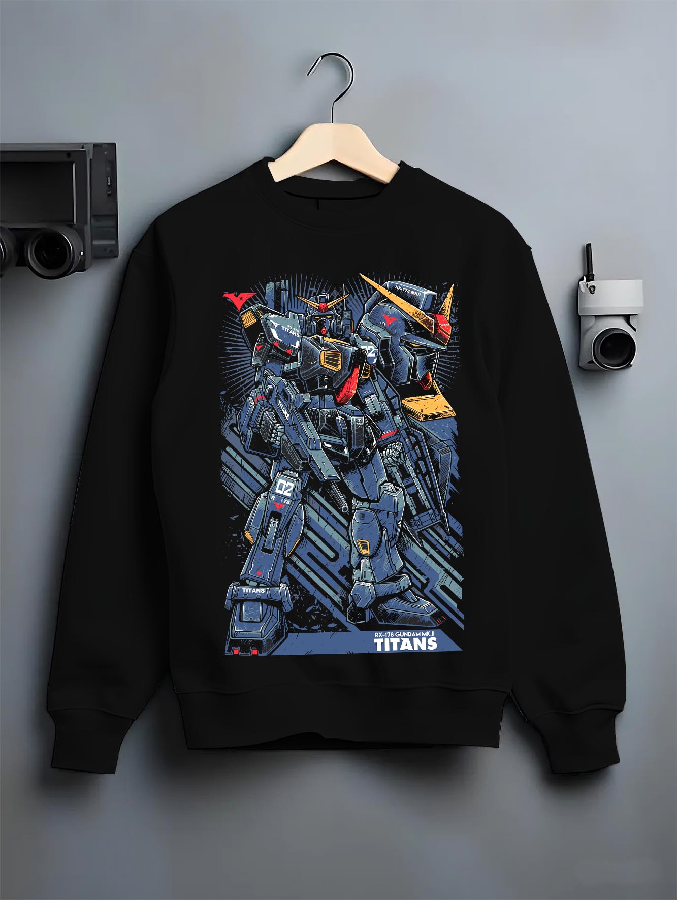 Black crewneck sweatshirt on a hanger against a grey wall, featuring Gundam Titans retro streetwear mecha artwork with anime poster inspired battle design.