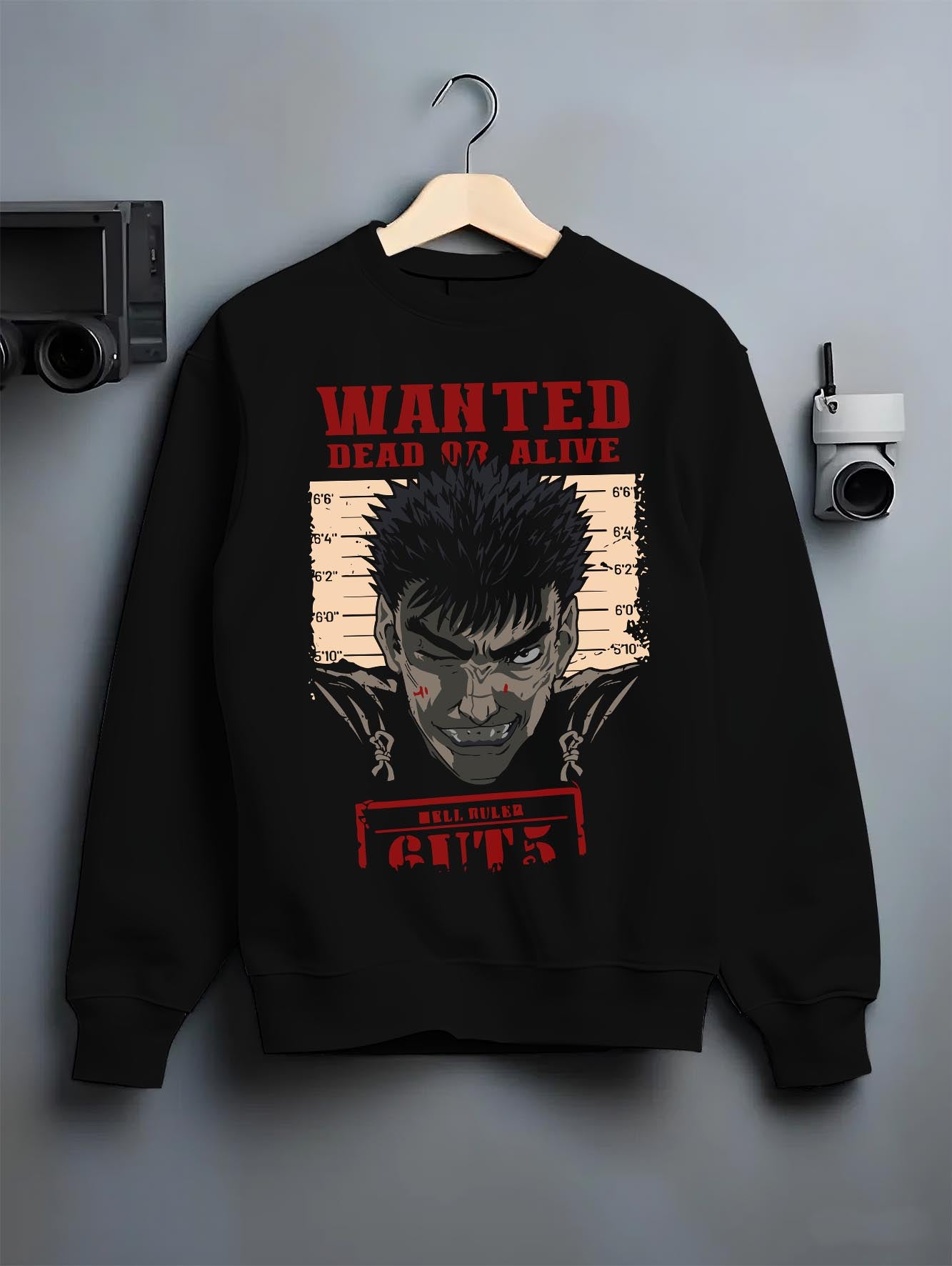 Black crewneck sweatshirt on a hanger against a grey wall, featuring Berserk retro manga wanted poster of Guts with striking red anime streetwear artwork.