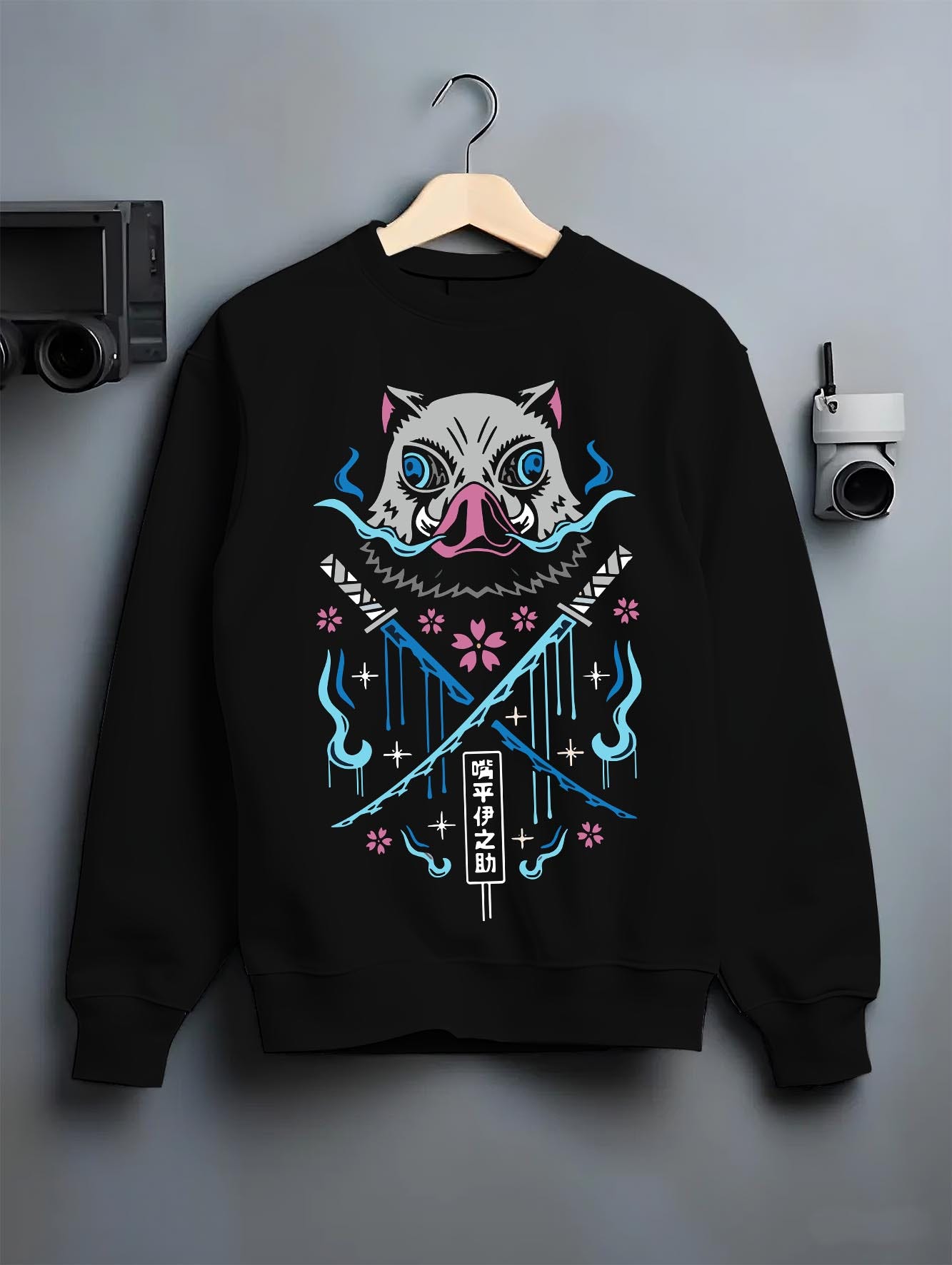 Black crewneck sweatshirt on hanger against grey wall, featuring Inosuke boar mask retro manga back graphic with crossed blades and blue flames.