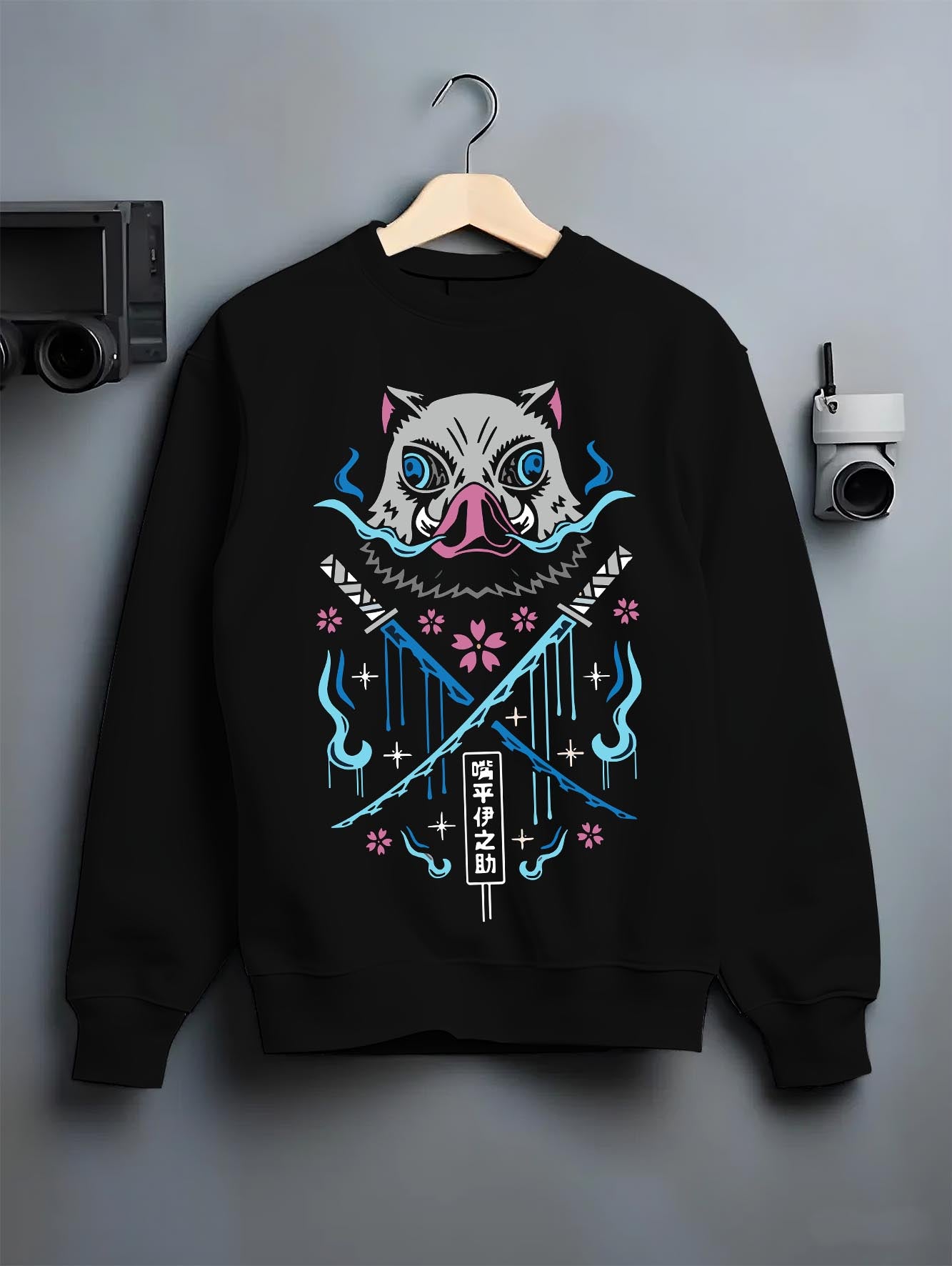 Black crewneck sweatshirt on hanger against grey wall, featuring Inosuke boar mask retro manga back graphic with crossed blades and blue flames.