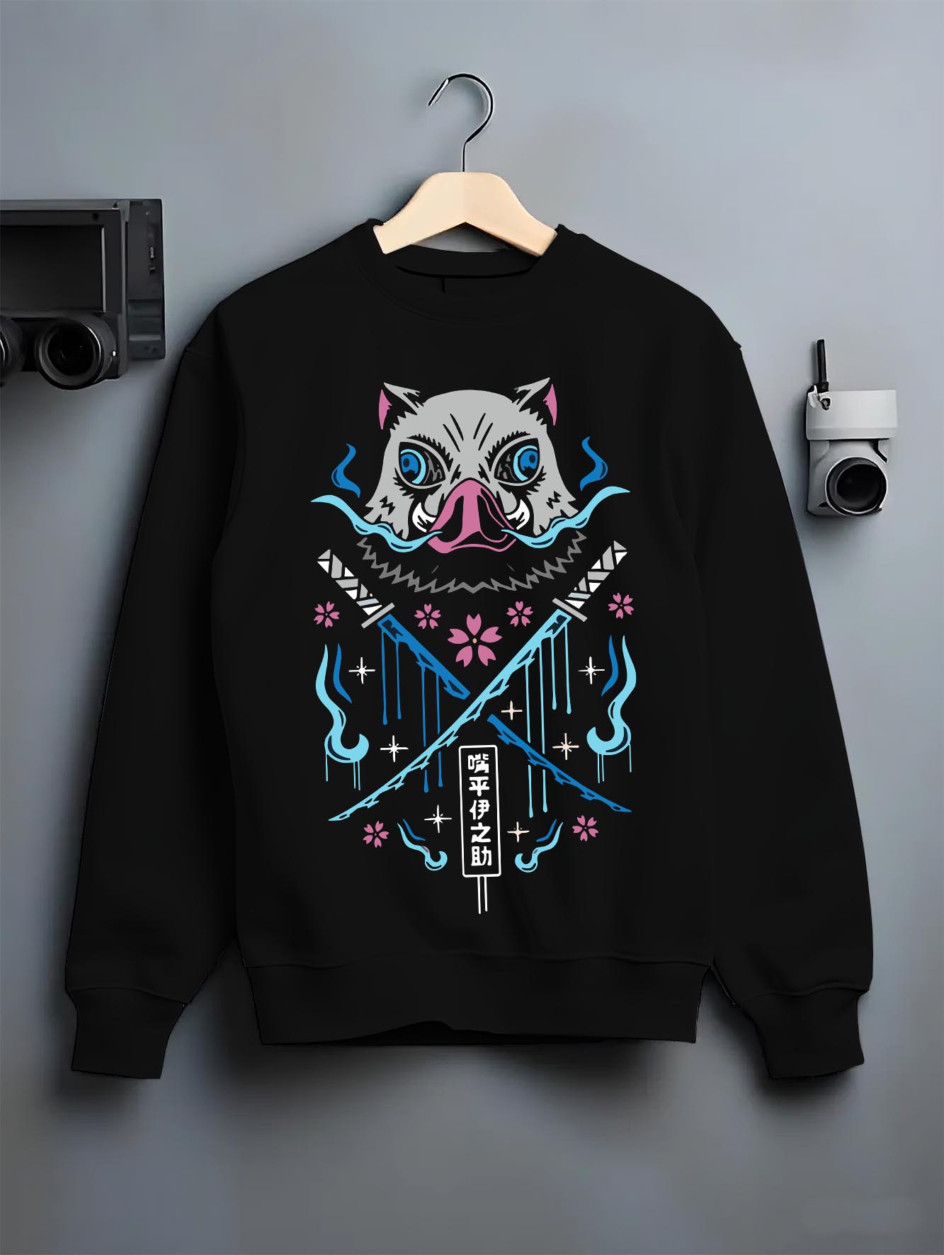 Black crewneck sweatshirt on hanger against grey wall, featuring Inosuke boar mask retro manga back graphic with crossed blades and blue flames.