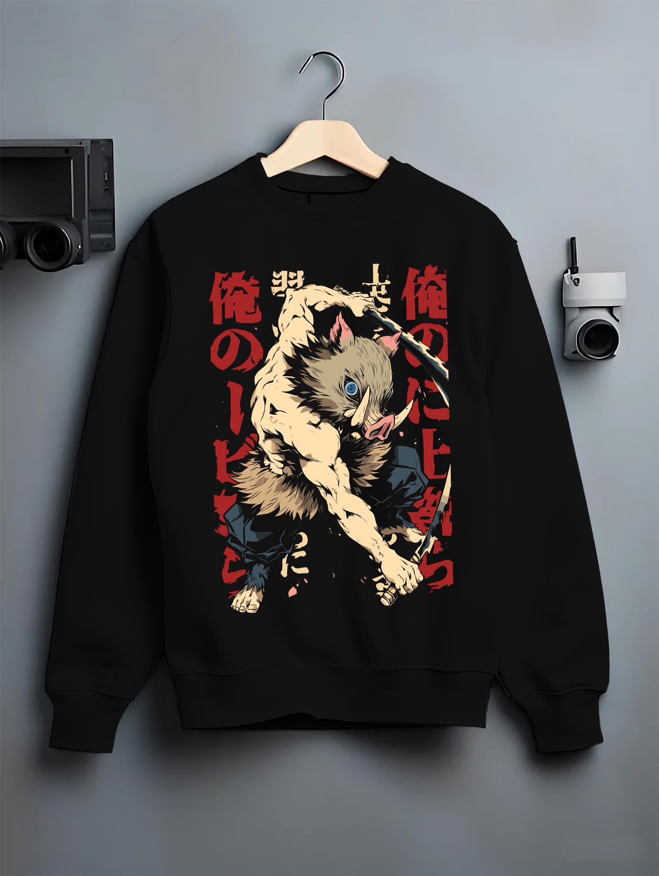 Black crewneck sweatshirt on a hanger against a grey wall, featuring Inosuke Demon Slayer retro streetwear graphic with bold boar mask warrior in battle design.