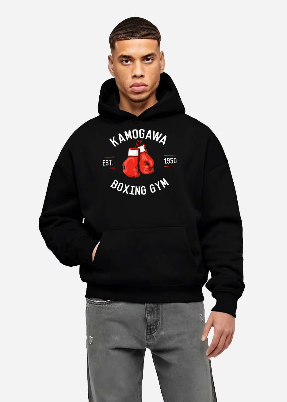 Black hoodie worn by a male model, back view, featuring Kamogawa Boxing Gym urban fashion back design with bold red boxing gloves and retro athletic style.