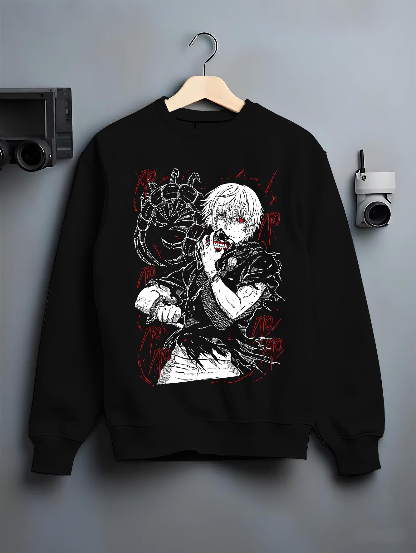 Black crewneck sweatshirt on a hanger against a grey wall, featuring Kaneki Tokyo Ghoul anime graphic artwork with retro manga panel red accent design.