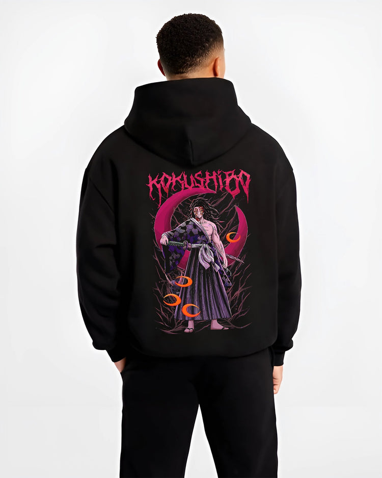 Black hoodie worn by a male model, back view, featuring Kokushibo Demon Slayer retro manga graphic with red moon, dual swords, and Japanese animation streetwear feel.