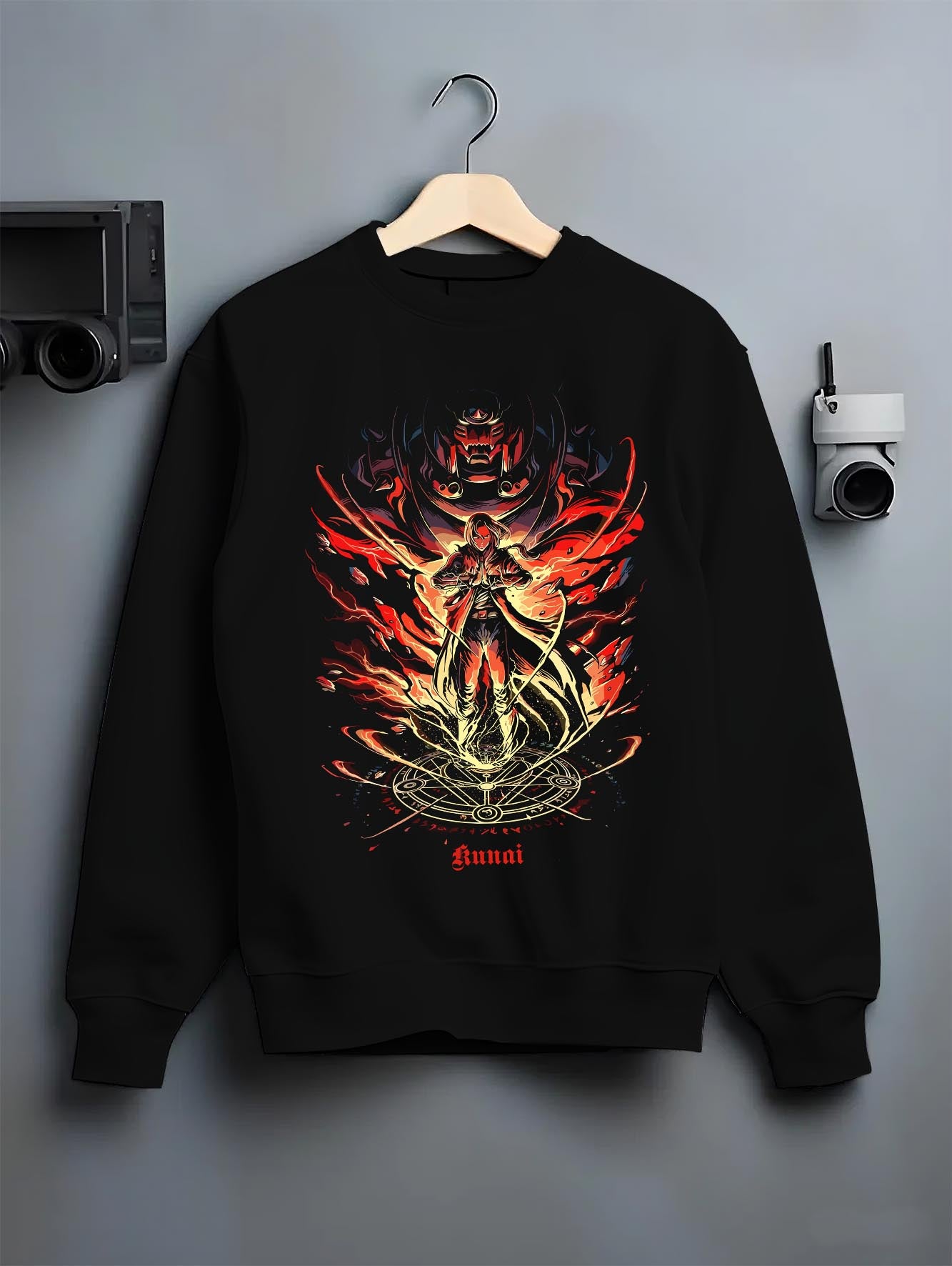 Black crewneck sweatshirt on a hanger against grey wall, featuring Kunai urban fashion back design of alchemy circle, sigils, and rising fire.