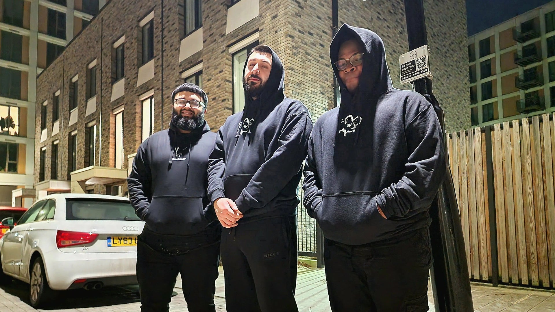 Three models wearing black Kunai anime hoodies in urban night streetwear scene, showcasing premium Japanese-inspired apparel for anime and manga fans in the UK.
