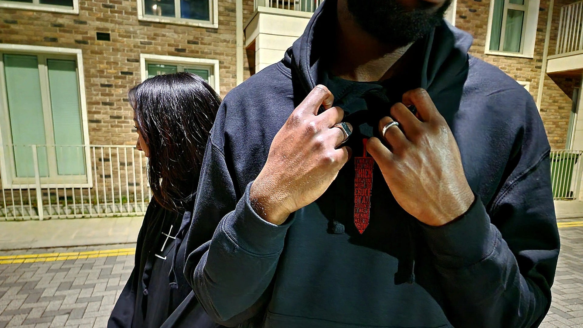 Two models wearing black anime hoodies from Kunai in night street setting, premium Japanese streetwear design inspired by manga culture and minimalist anime fashion.
