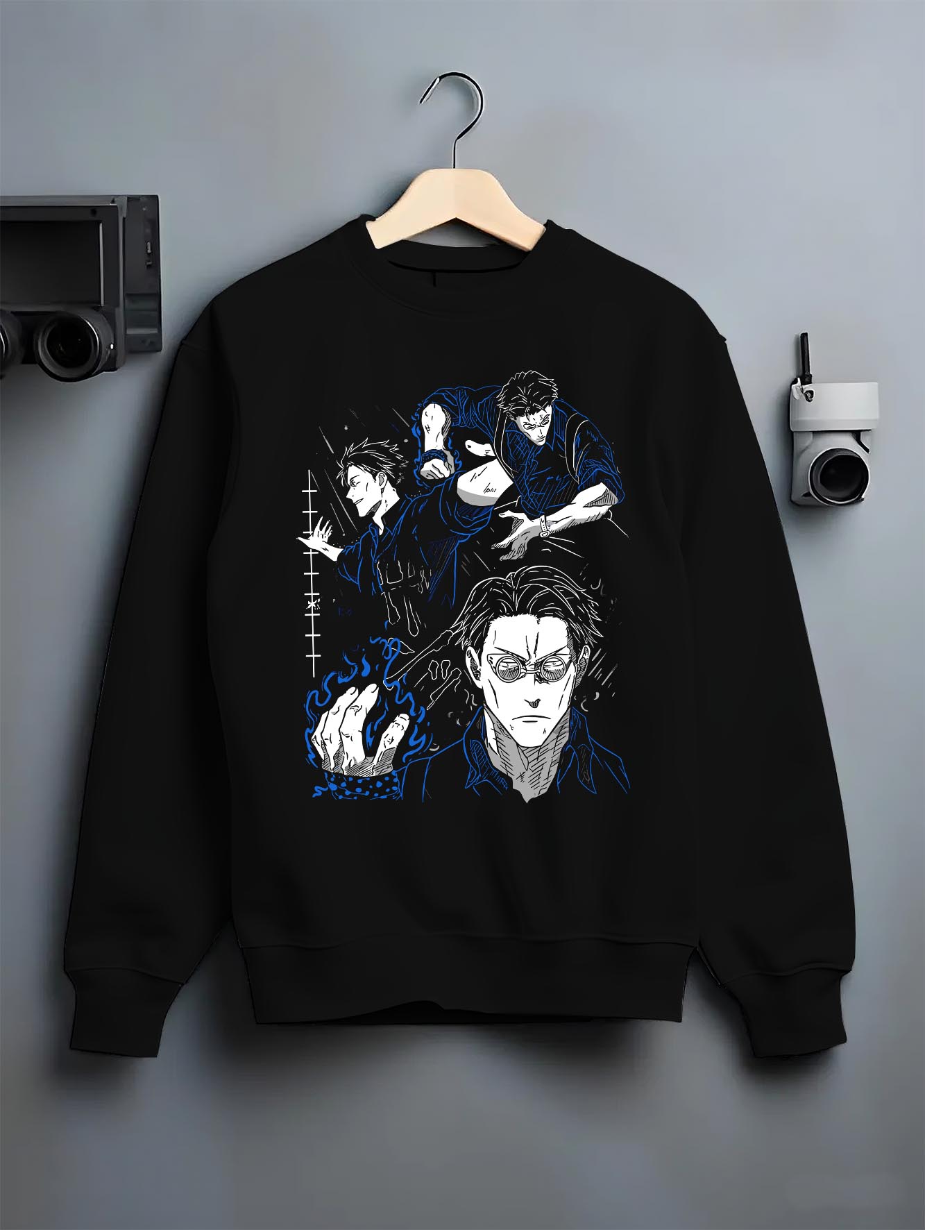 Black crewneck sweatshirt on a hanger against a grey wall, featuring Kento Nanami modern streetwear graphic with retro manga panel aesthetic in blue highlights.