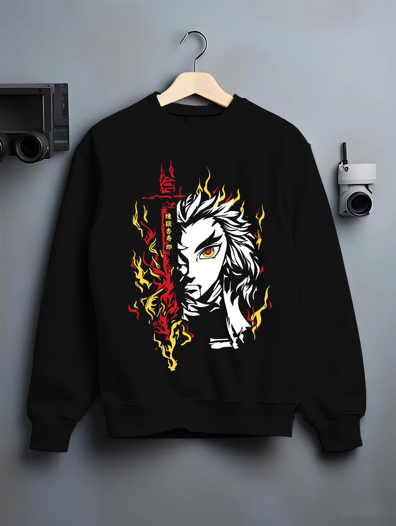 Black crewneck sweatshirt on hanger against grey wall, Rengoku manga portrait with vertical kanji and blazing sword flames.