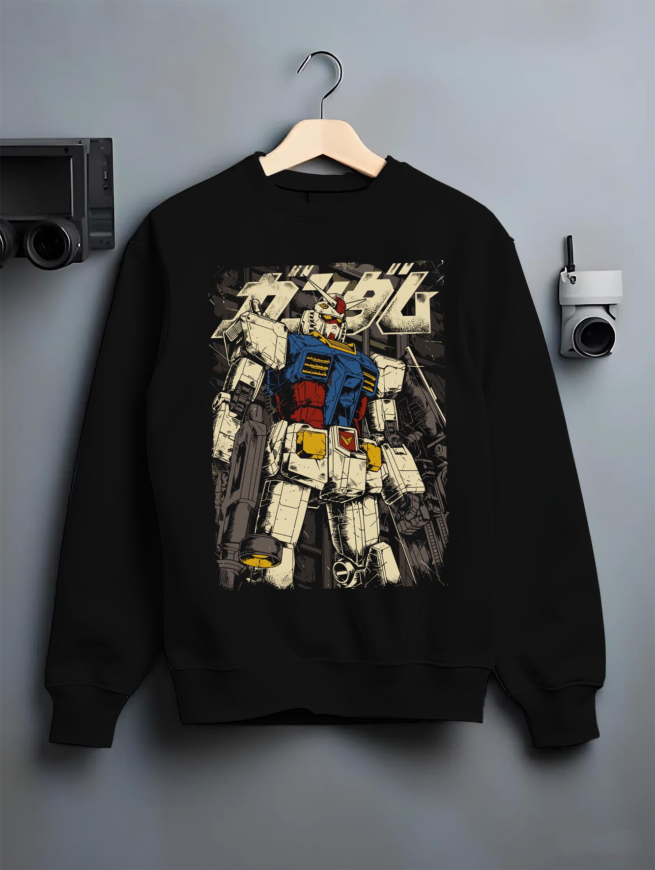 Black crewneck sweatshirt on a hanger against a grey wall, featuring RX-78-2 Gundam retro mecha anime poster inspired back design in classic vintage manga tones