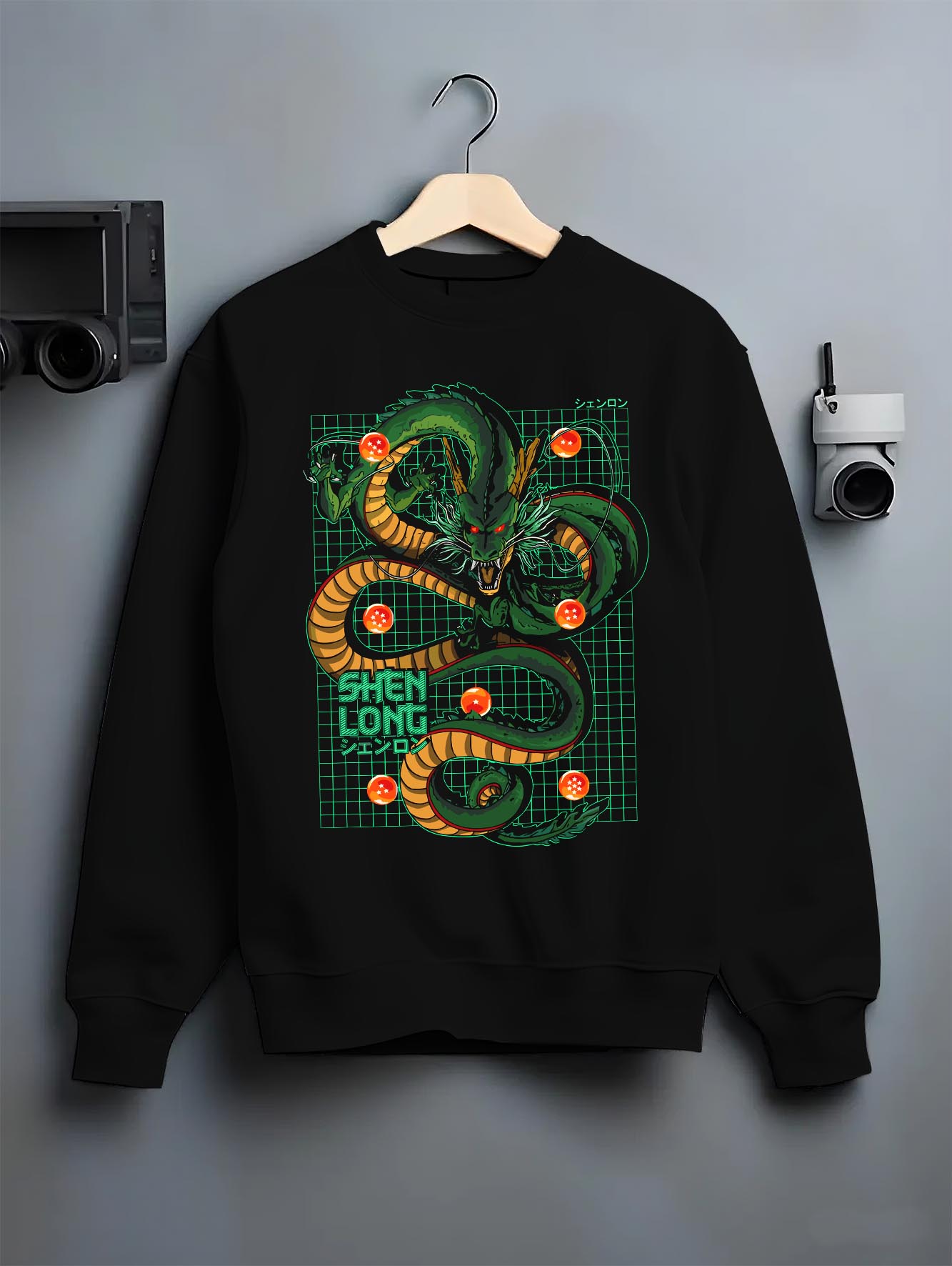 Black crewneck sweatshirt on a hanger against a grey wall, featuring Shenron anime poster inspired Dragon Ball design with retro manga dragon artwork.