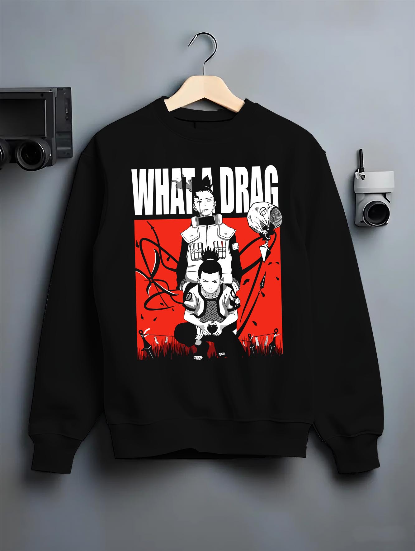 Black crewneck sweatshirt on hanger against grey wall, featuring Shikamaru Naruto anime poster style graphic with red panel and caption.