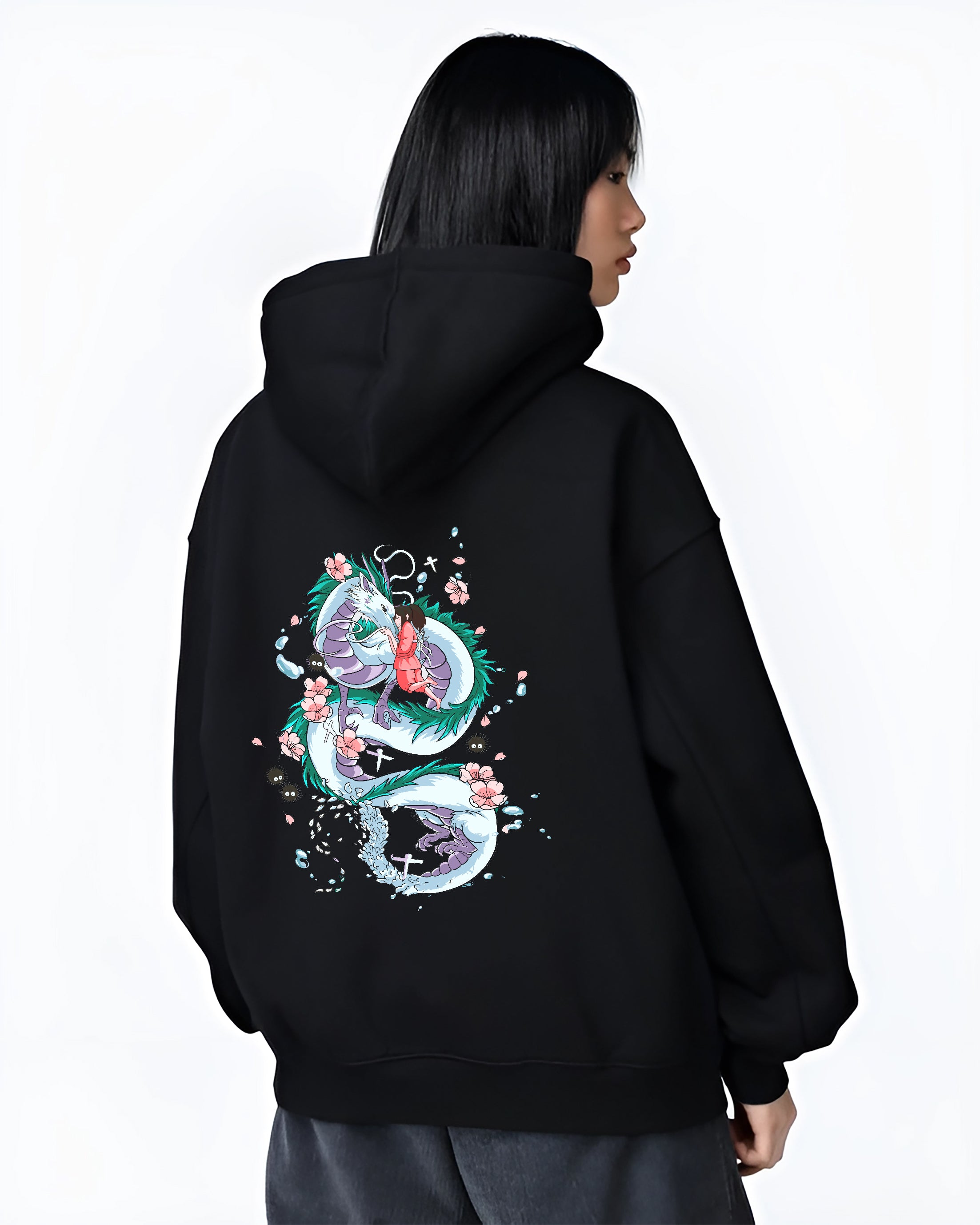 Black hoodie on female model, back view, featuring Spirited Away Haku and Chihiro nostalgic 90s graphic with petals and soot sprites.