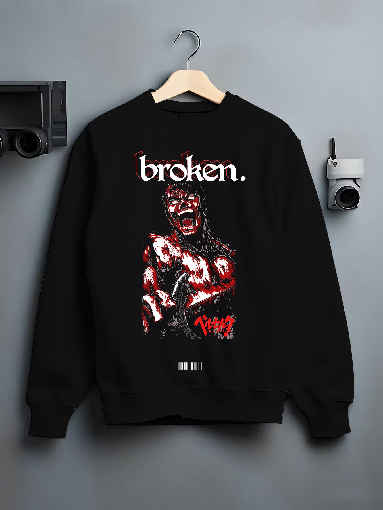 Black crewneck sweatshirt on a hanger against a grey wall, featuring Berserk Guts dark manga panel inspired design with blood-red retro streetwear artwork style.
