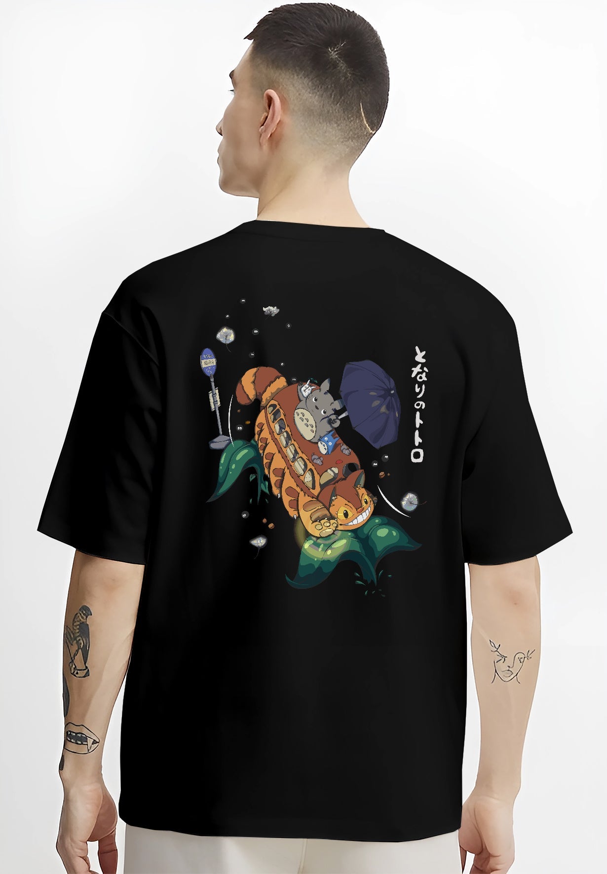 Black T-shirt on male model, back view, Totoro and Catbus nostalgic 90s graphic with umbrella and leaf wave accents.