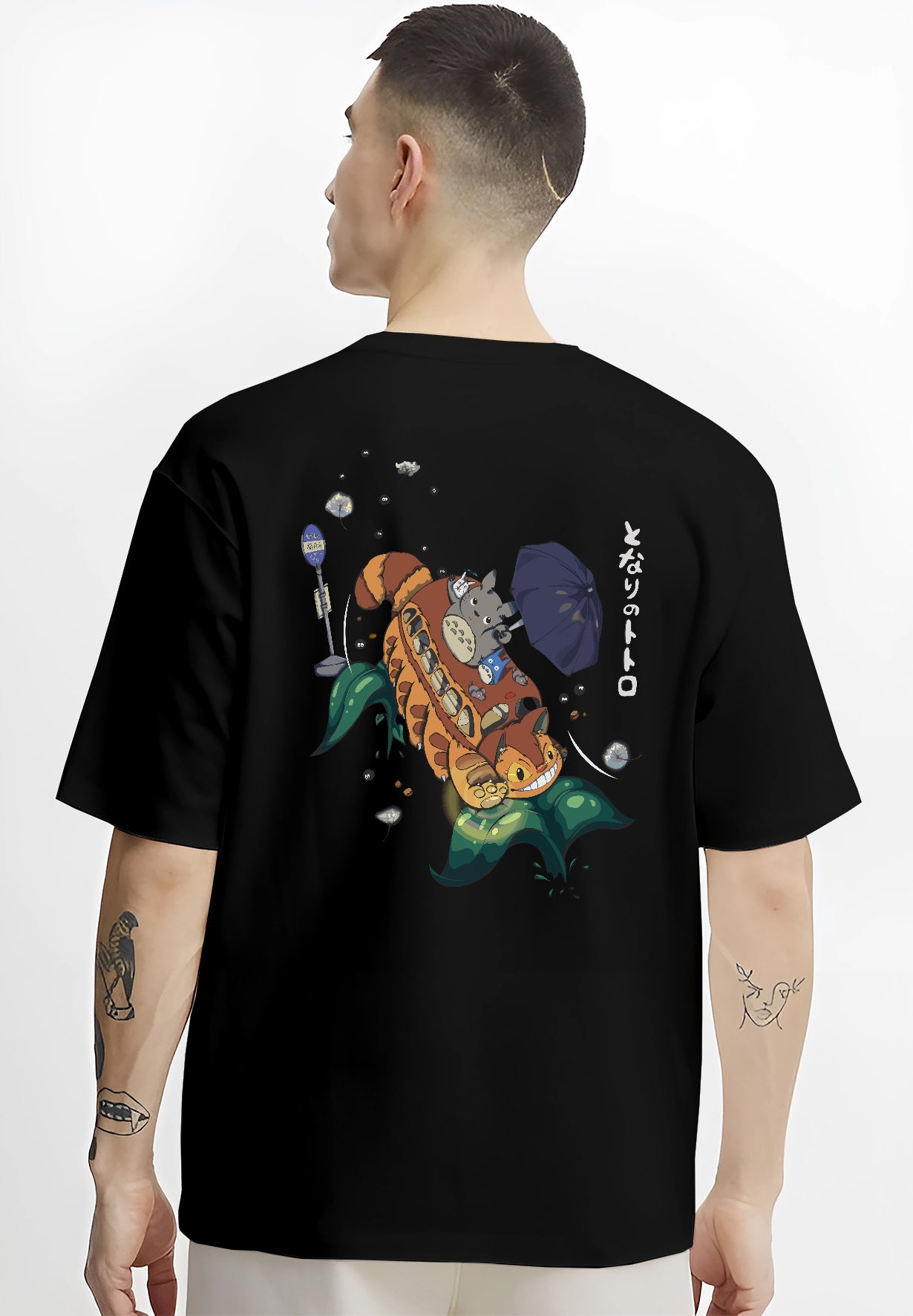 Black T-shirt on male model, back view, Totoro and Catbus nostalgic 90s graphic with umbrella and leaf wave accents.