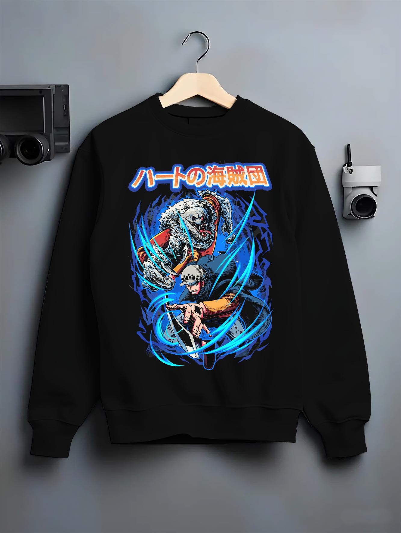 Black crewneck sweatshirt on hanger against grey wall, One Piece Trafalgar Law and Bepo back graphic with blue energy and manga styling.