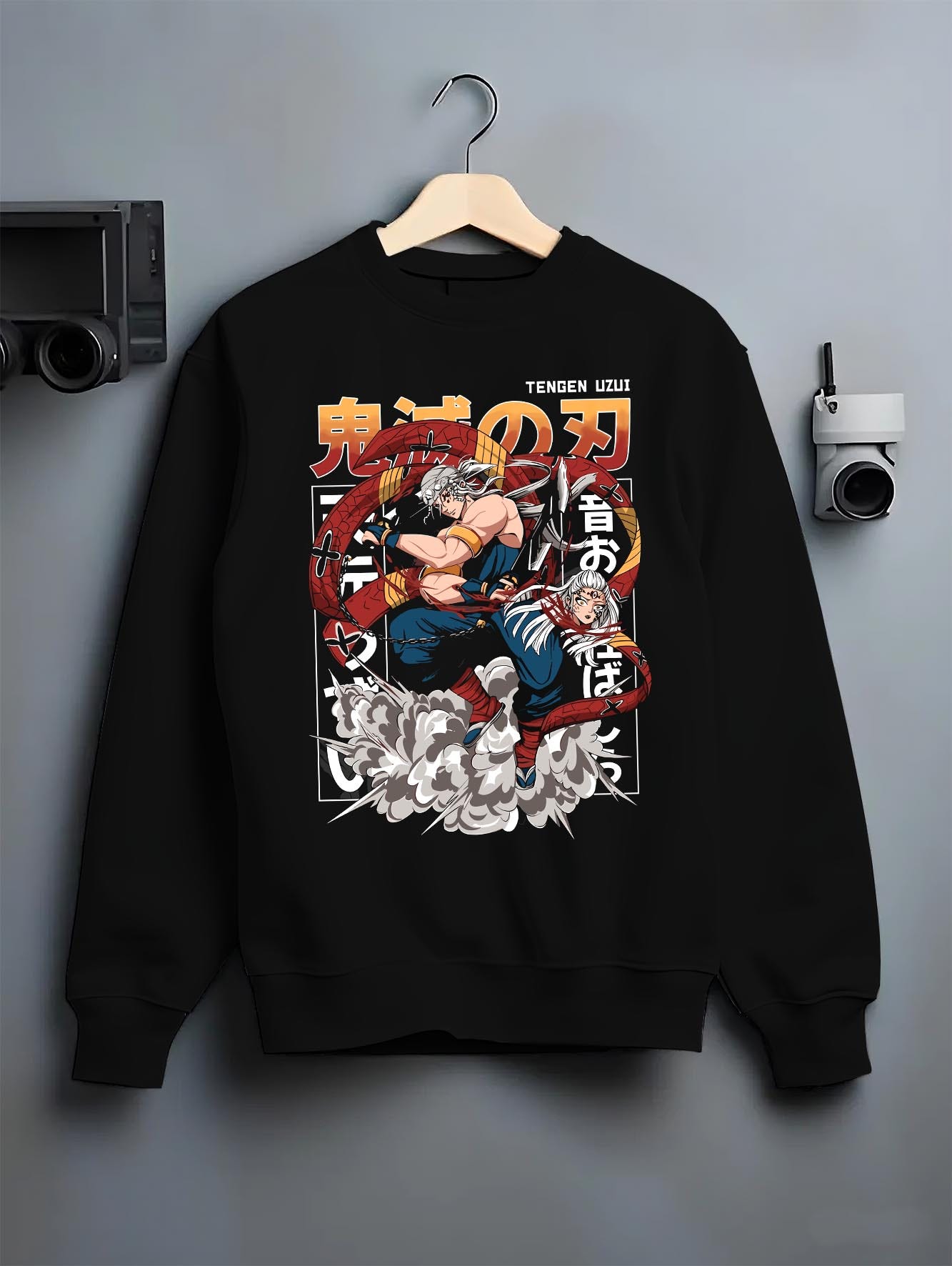 Black crewneck sweatshirt on a hanger against a grey wall, featuring Tengen Uzui modern streetwear graphic with explosive energy and motion.