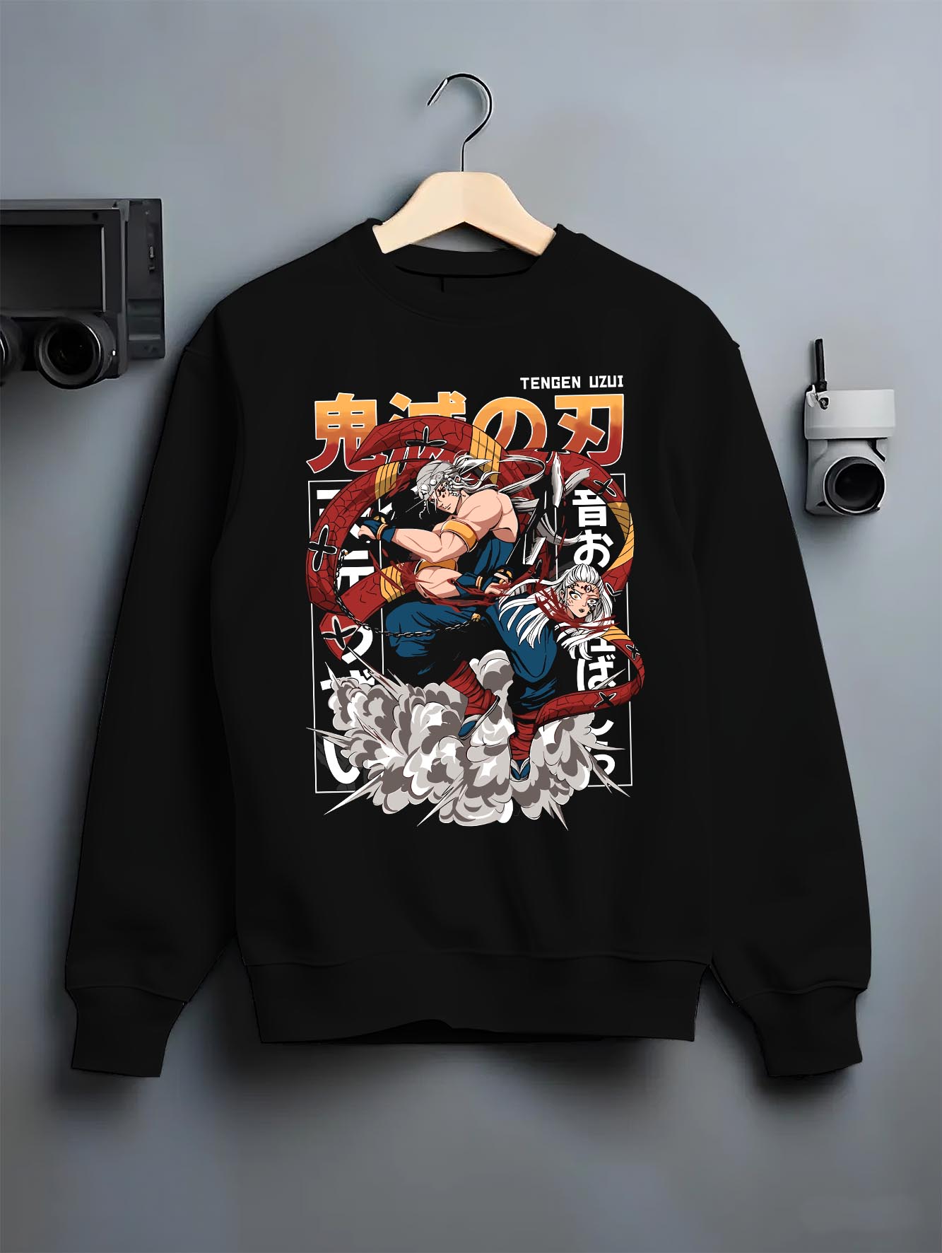 Black crewneck sweatshirt on a hanger against a grey wall, featuring Tengen Uzui modern streetwear graphic with explosive energy and motion.