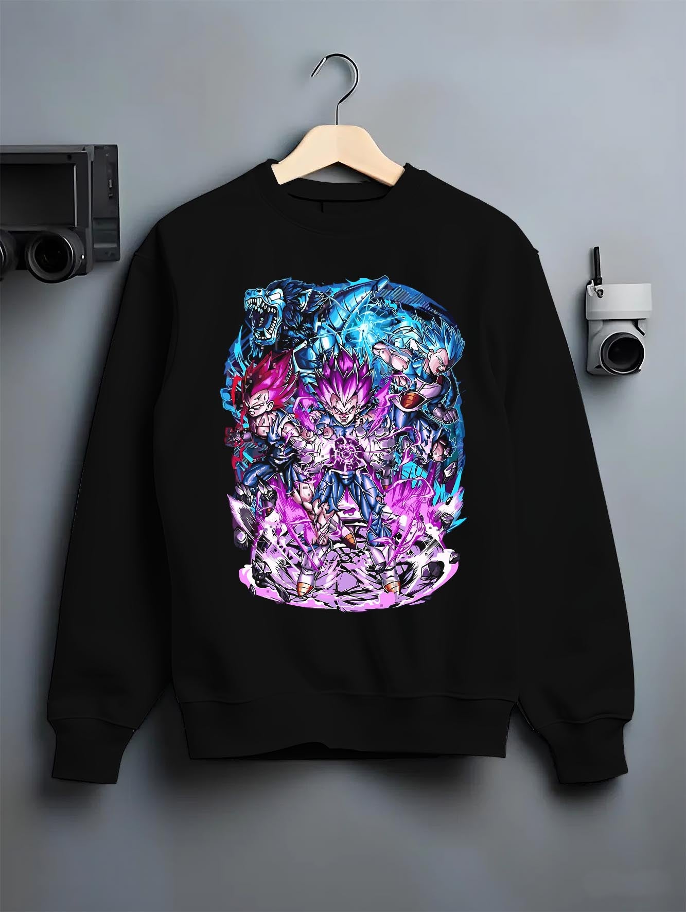 Black crewneck sweatshirt on a hanger against a grey wall, featuring Vegeta Dragon Ball retro streetwear graphic with electrifying purple aura and bold manga details.