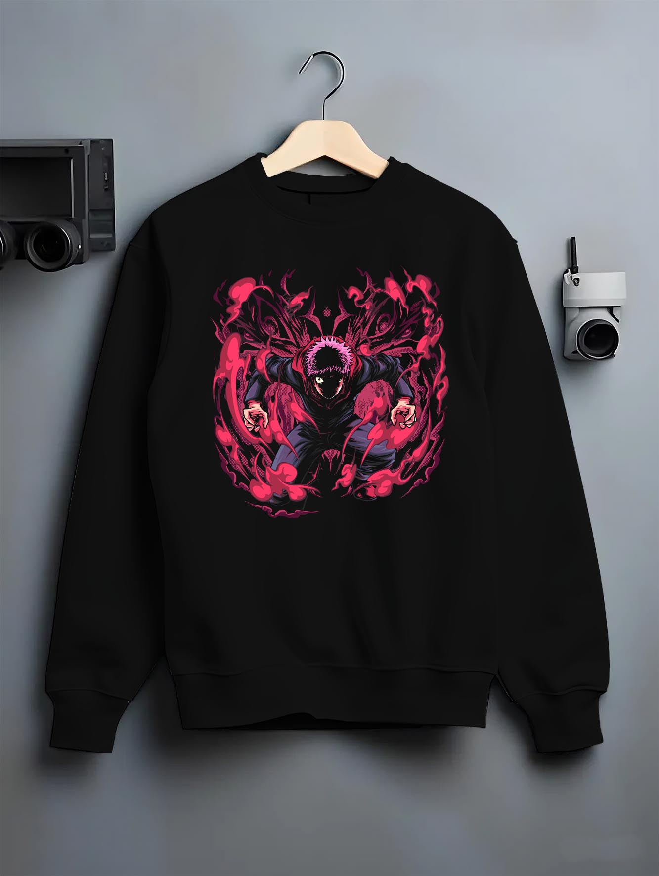 Black crewneck sweatshirt on hanger against grey wall, Yuji Itadori anime poster back graphic with bold red cursed aura.